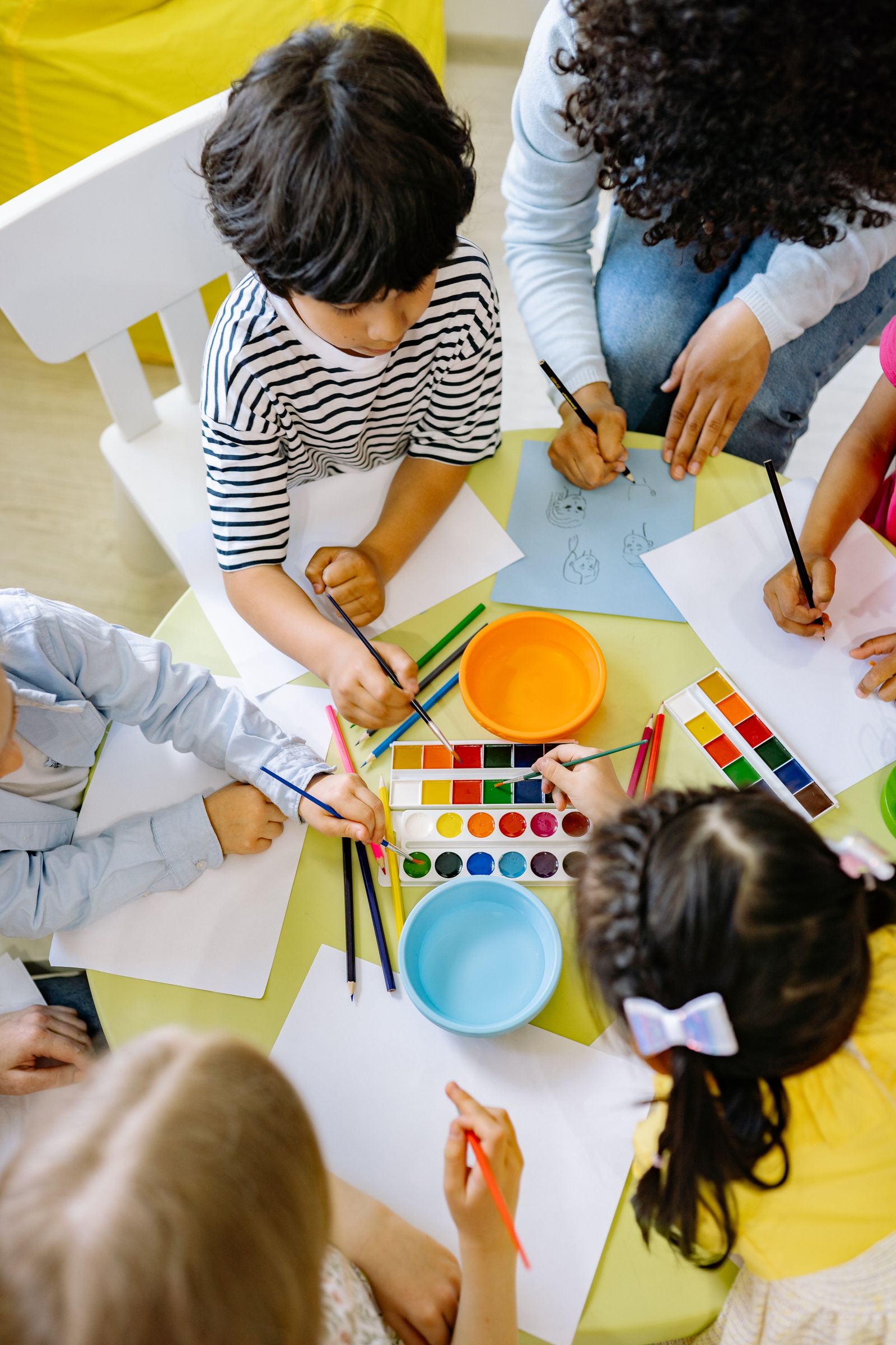 Children painting with colourful watercolours on a table during an art class.
