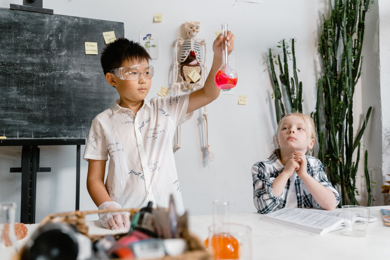 Two students conducting a chemistry experiment with flasks and beakers in a school science laboratory.