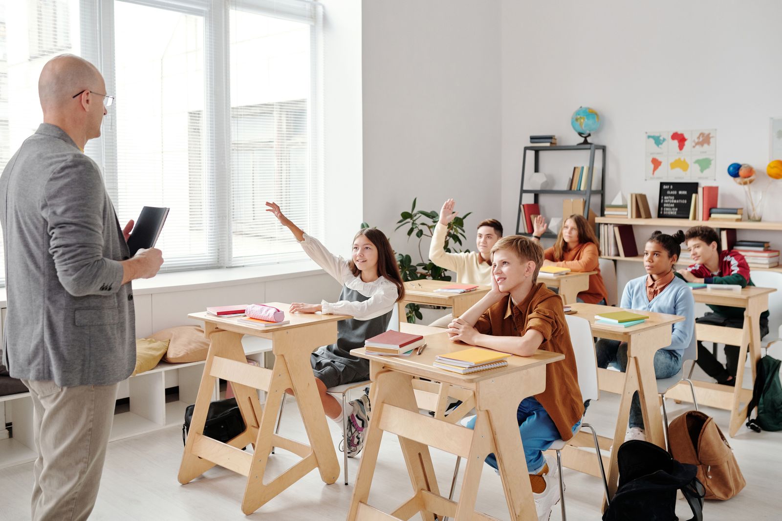 Students eagerly raising their hands to answer during a classroom lesson.