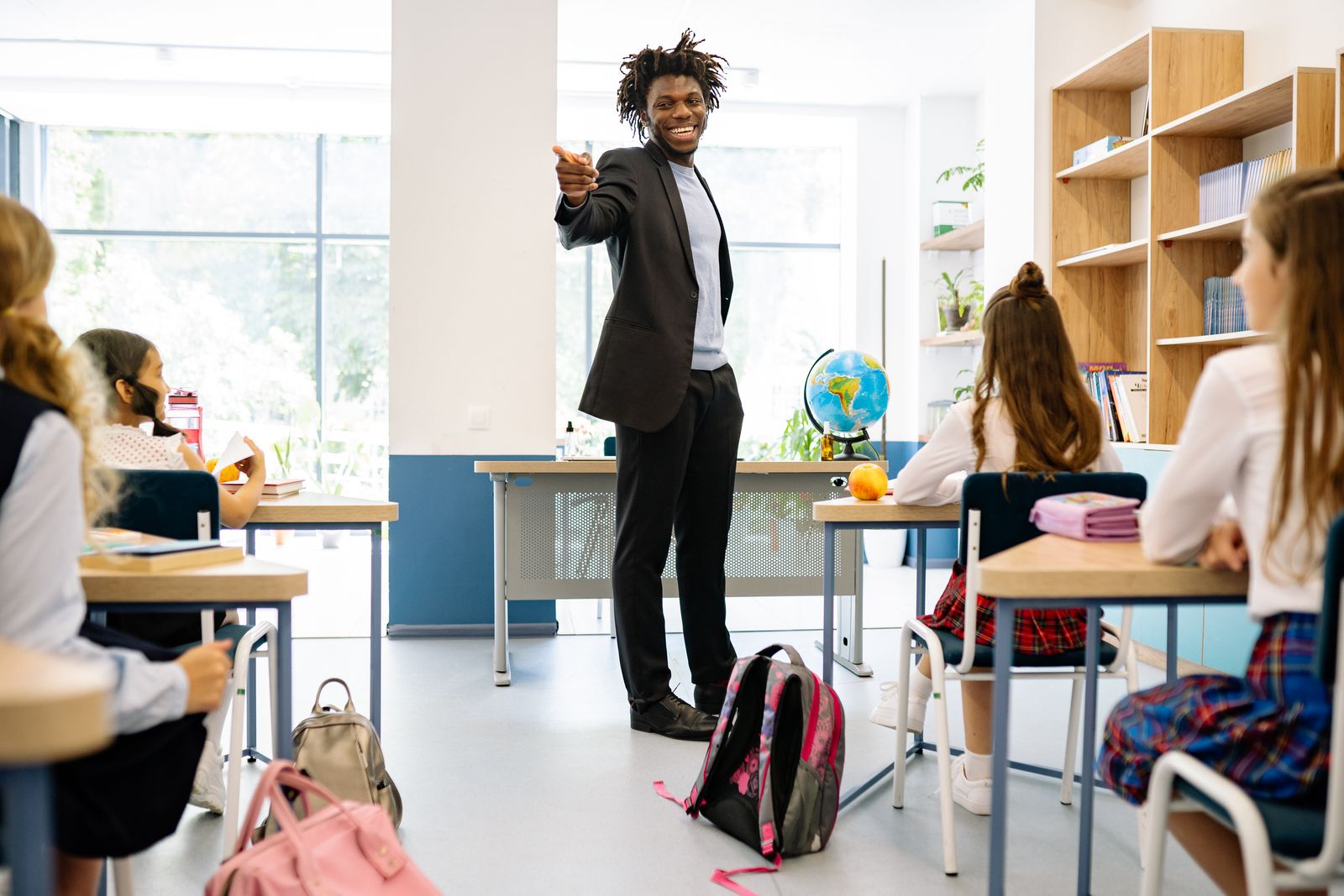 A teacher leading a lesson in a bright classroom while a diverse group of students listens and takes part.