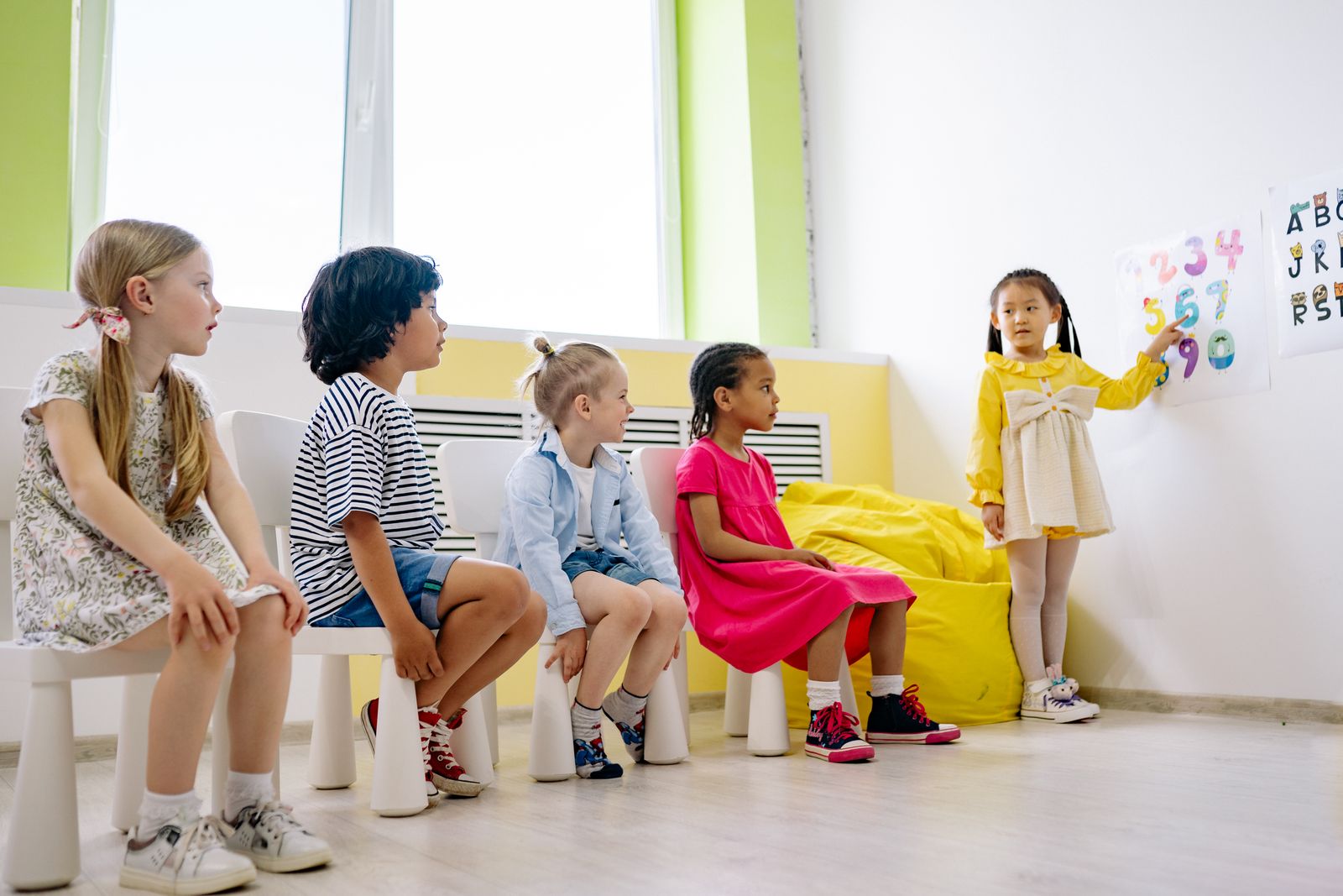 Young primary-age children taking part in a colourful lesson in their classroom.